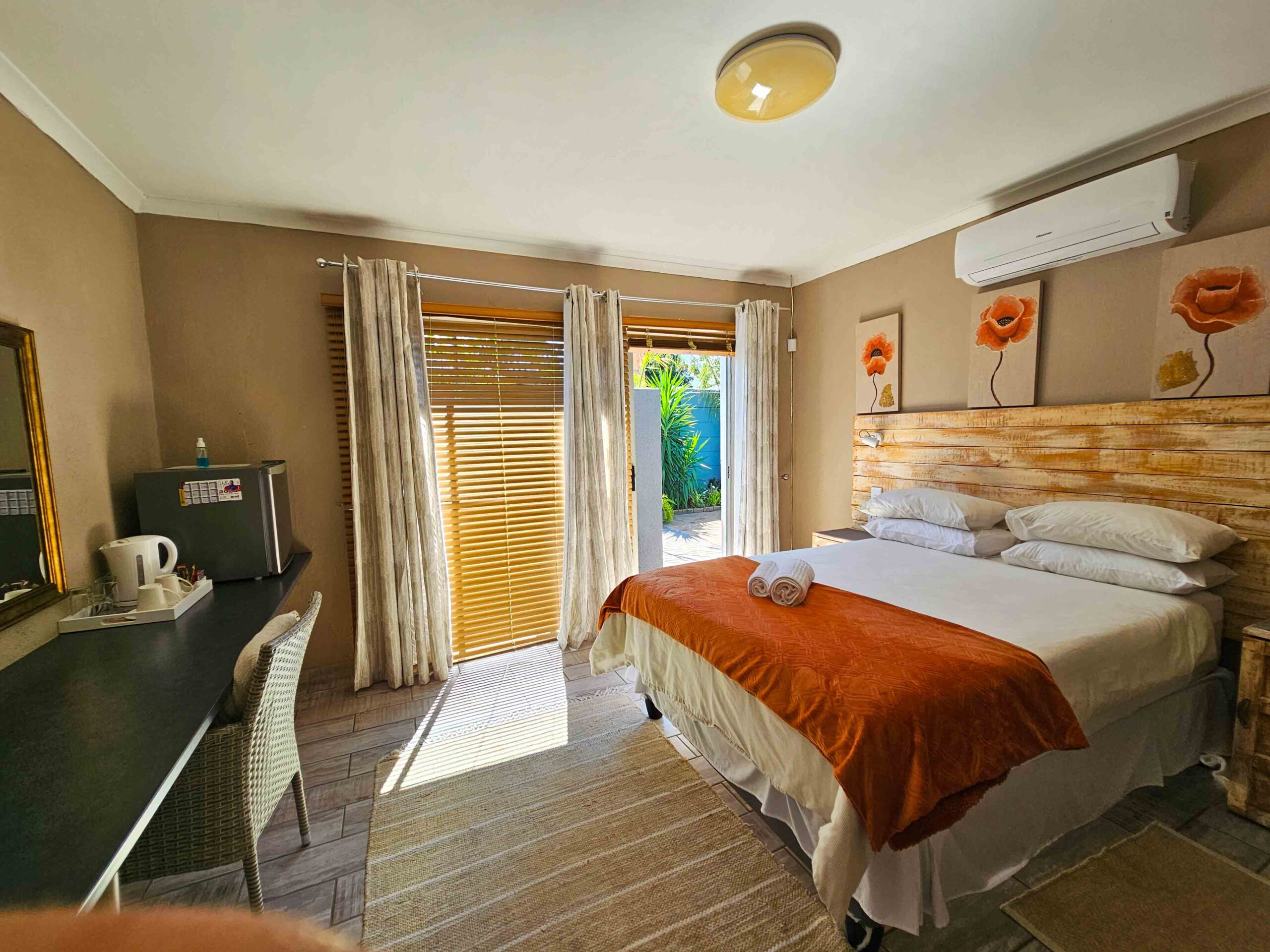 Cozy and inviting bedroom at Northern Vine B&B in Brackenfell, featuring a comfortable queen-size bed, a writing desk, and access to an outdoor space.